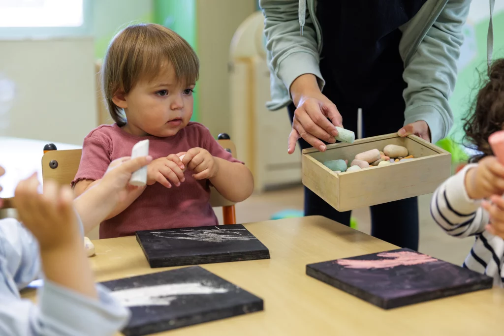 Un jeune enfant participe à un atelier ardoise et craies dans une micro-crèche.