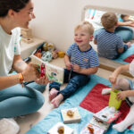 Professionnelle de la petite enfance lit un livre à deux enfants souriants