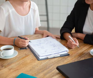 Young female colleagues meeting and discussing business plan, writing strategy scheme on paper, making draft. Cropped shot. Planning concept